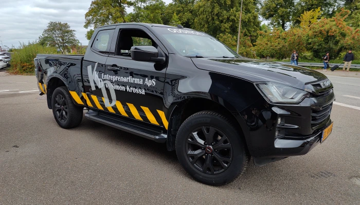 Sort Isuzu pickup for KLD Entreprenørfirma folieret af Gylling Skilte – robust og markant design med gule advarselsdetaljer for et professionelt udtryk.