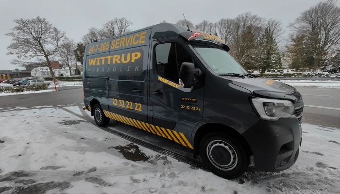 24/7 servicebil for Wittrup Hydraulik designet og folieret af Gylling Skilte – moderne og funktionelt udtryk i mørkegrå og gule farver, der fremhæver virksomhedens døgnservice og professionelle profil.